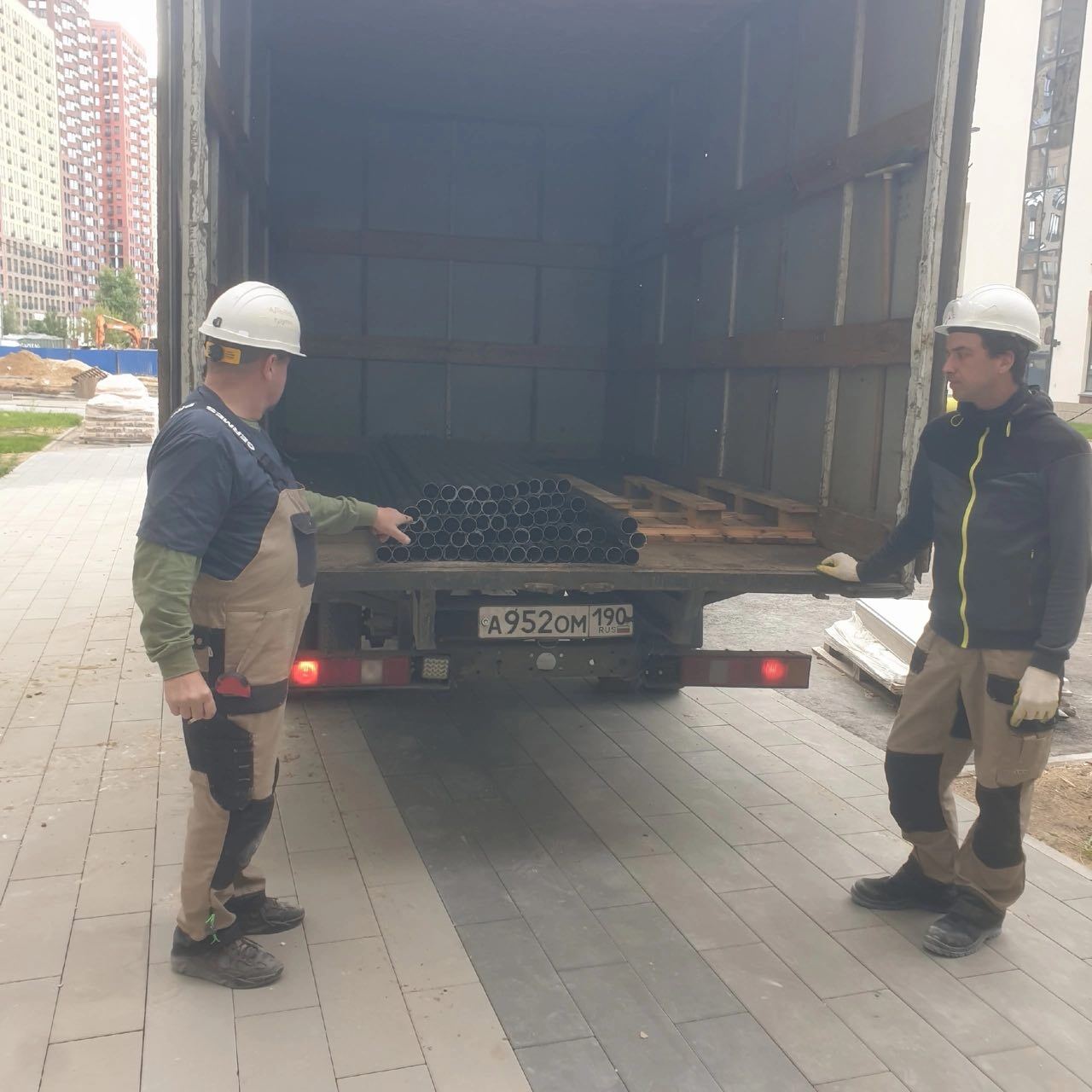 Двое рабочих в касках принимают груз с борта